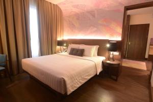 a bedroom with a large white bed with a painting on the wall at Mercure Karawang in Karawang