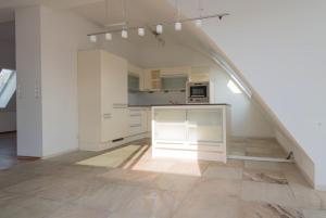 an attic kitchen with white cabinets and a staircase at Rennweg Top Apartment in Vienna