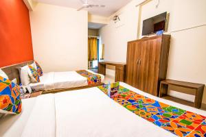 um quarto de hotel com duas camas e uma televisão em FabHotel Kumar Vijay Nagar em Indore