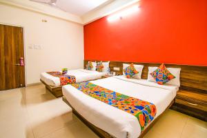 duas camas num quarto com uma parede vermelha em FabHotel Kumar Vijay Nagar em Indore