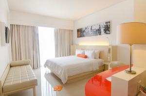 a hotel room with a bed and a desk with a lamp at HARRIS Hotel and Conventions Denpasar Bali in Denpasar