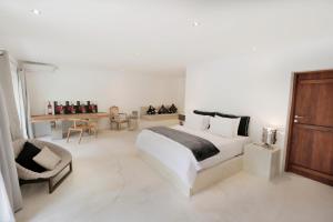 a white bedroom with a large bed and a chair at The Apartments Ubud in Ubud