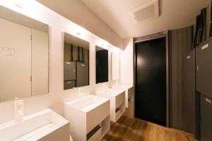 a bathroom with three sinks and two mirrors at MANGA ART HOTEL, TOKYO in Tokyo