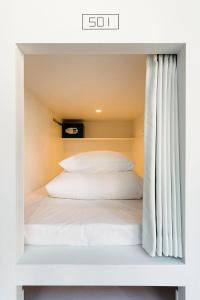 Cama en habitación pequeña con cortina en MANGA ART HOTEL, TOKYO, en Tokio