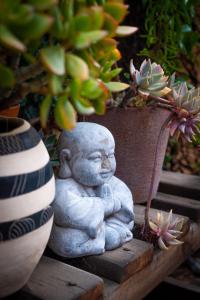 una estatua de un niño pequeño sentado junto a una planta en Treetops Guesthouse, en Port Elizabeth
