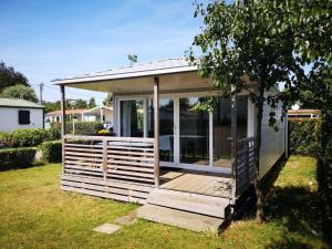 una pequeña casa con un porche en un patio en Camping La Forêt Stella-Plage, en Stella-Plage