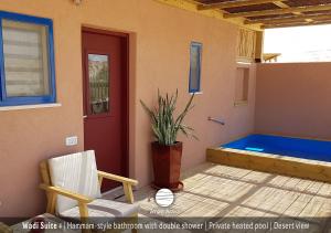 a patio with a hot tub next to a red door at Zman Arava in Zuqim