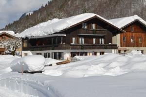 a house covered in snow in front of it at Landhaus Spielmannsau in Oberstdorf