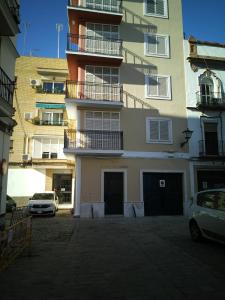 un edificio alto con coches estacionados frente a él en TRIANA RUISEÑOR en Sevilla