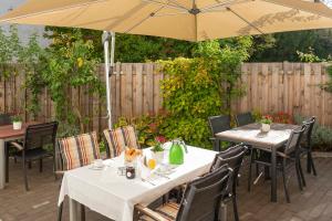 zwei Tische und Stühle unter einem Sonnenschirm auf einer Terrasse in der Unterkunft Hotel Westerfeld in Hemmingen