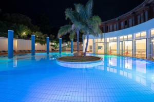a swimming pool at night with a palm tree in the middle at Hotel Club Village Maritalia in Peschici