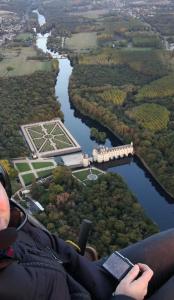 een persoon met een mobiele telefoon die naar een rivier kijkt bij gîte papillon 4 in Civray-de-Touraine