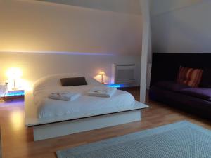 een slaapkamer met een wit bed en een bank bij Le Prana - Les Chambres d'Hôtes, Wellness et Centre de soins in Rozérieulles