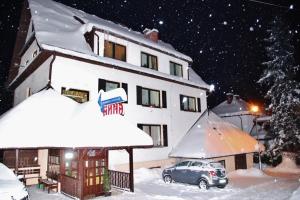a building with a car parked in the snow at Dom Wczasowy Anna in Rabka-Zdrój