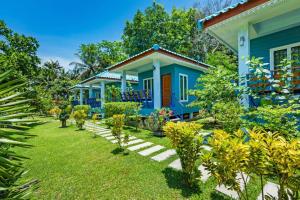 a blue house with a garden in front of it at RAT VILLA in Ban Pa Khlok