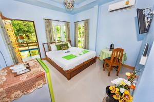 a bedroom with a bed and a table and a chair at RAT VILLA in Ban Pa Khlok