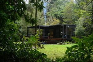 a cabin in the woods with a grass yard at Wongari Eco Retreat in Lamington
