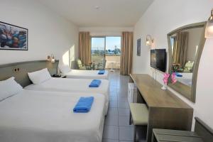 a hotel room with two beds and a television at Nissiana Hotel & Bungalows in Ayia Napa +63 photos