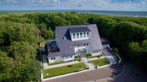 诺德奈Storchennest Norderney的享有白色房子的顶部景色,那里有树木和水