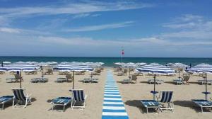 a beach with blue and white chairs and umbrellas at Residence 3 Oblò in Giulianova