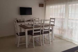 einen Esstisch mit weißen Stühlen und einen TV in der Unterkunft COQUETO APARTAMENTO EN PLAYA DE ARO in Platja  d'Aro