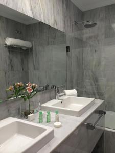 a bathroom with a sink, mirror, and bath tub at Hotel Rector in Salamanca