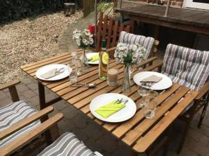 a wooden picnic table with plates and flowers on it at Haus Ihlkatenweg in Kiel