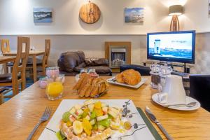 una mesa con un plato de comida y una TV en The Trout Fly Guest House, en Port Ellen