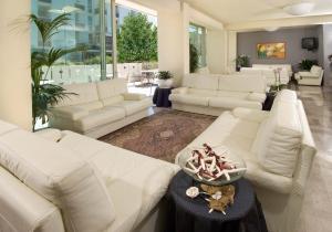 un soggiorno con divani bianchi e tavolo di Hotel Alba a Misano Adriatico