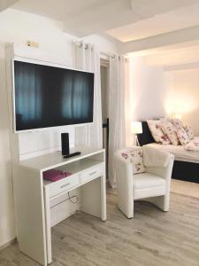 a white living room with a tv and a chair at Reikistudio Venedig in Quedlinburg