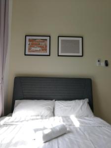 a bed with white sheets and two pictures on the wall at Desaru Arcadia Semi D Rooms Rental Available in Desaru
