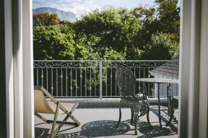 un patio con 2 sillas y una mesa en el balcón en The Victorian Goose, en Ciudad del Cabo