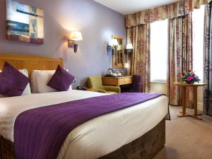 a hotel room with a large bed with purple sheets at Durley Dean in Bournemouth