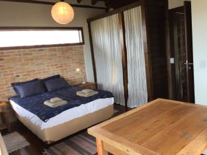 1 dormitorio con cama y mesa de madera en Casa Linda e Aconchegante, en Imbituba