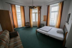 ein Schlafzimmer mit einem Bett, einem Sofa und Fenstern in der Unterkunft Apartment Kahoun in Prag
