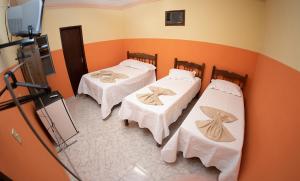three beds in a room with orange walls at Hotel Minas Brasil in Salinas