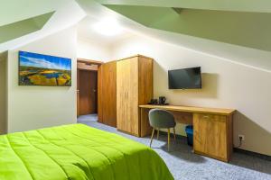a bedroom with a bed and a desk with a television at Szelesiówka & SPA in Chodzież