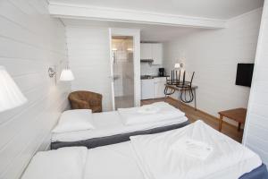 um quarto branco com 2 camas e uma cadeira em Midttun Motell & Camping AS em Bergen