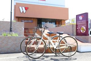 千歳市にあるホテルウィングインターナショナル千歳の建物の前に自転車2台が駐車しています。 +37枚の写真