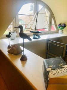 a bird statue on a table with a sail boat in a window at "Netzboden" by Ferienhaus Strandgut in Born