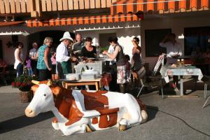 a statue of a cow sitting on the ground with people at Pichlerhof in Riva di Tures