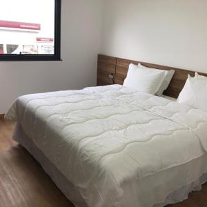 a large white bed in a bedroom with a window at Hotel Matrix in Apucarana