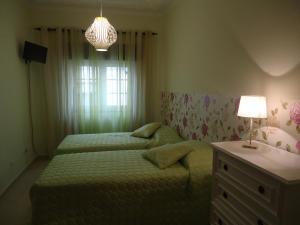 a bedroom with two beds and a table and a lamp at Quarto in Alvor