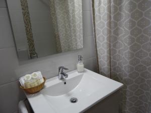 un lavandino in bagno con specchio e tenda per la doccia di Casa Julieta ad Alvor Altre 29 foto