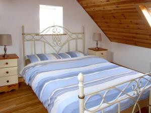 a bedroom with a large white bed with blue stripes at 1 Clancy Cottages in Kilkieran