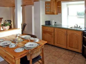 a kitchen with a wooden table with plates on it at 1 Clancy Cottages in Kilkieran