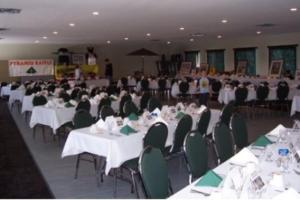 a banquet hall with white tables and green chairs at Fisherman's Landing Inn in Rocky Harbour