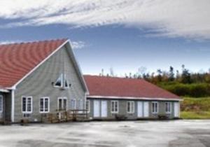 un gran edificio gris con techo rojo en Fisherman's Landing Inn, en Rocky Harbour