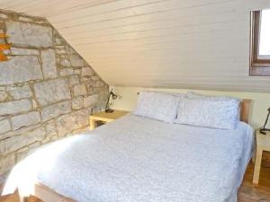 a bedroom with a white bed and a stone wall at Clooncorraun Cottage in Ballinrobe