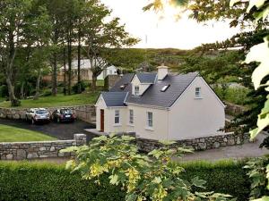 uma casa branca com carros estacionados numa garagem em 1 Clancy Cottages em Kilkieran